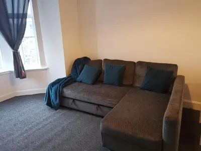 a living room with a brown couch with blue pillows at Castleview is a lovely flat in a listed building in Rothesay