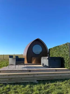 a wooden deck with two chairs and a hot tub at Endrick Escape - Luxury Glamping in Gartness