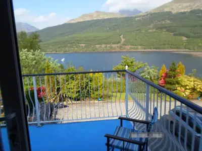 a balcony with two chairs and a view of a lake at Braemor 4 bedroom villa, all en-suite in Arrochar