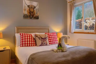 a bedroom with a bed with a bottle of wine on it at Gleann Fia House in Arrochar