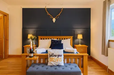 a bedroom with a bed with a black headboard at Gleann Fia House in Arrochar