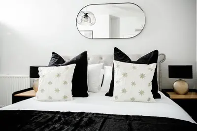 a bedroom with a bed with black and white pillows at 2 BDR House At Caledonia Luxe Stays Short Lets & Serviced Accommodation Crieff in Crieff