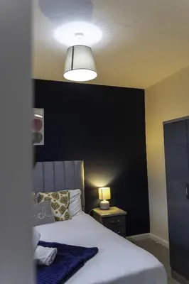 a bedroom with a bed with a black accent wall at Raploch House in Larkhall