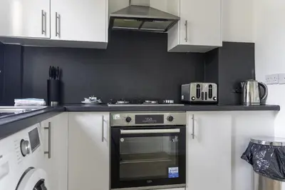 a kitchen with white cabinets and an oven at Raploch House in Larkhall