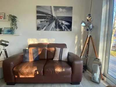 a brown leather couch in a living room with a camera at the waterside - carrick castle - loch goil in Carrick