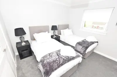a bedroom with two beds and a window at Lovely 2 Bedroom Flat in a quiet location in Airdrie