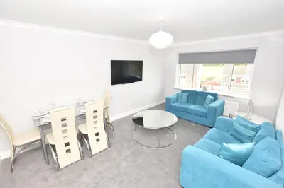 a living room with a blue couch and a table and chairs at Lovely 2 Bedroom Flat in a quiet location in Airdrie