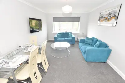 a living room with a blue couch and a table and chairs at Lovely 2 Bedroom Flat in a quiet location in Airdrie