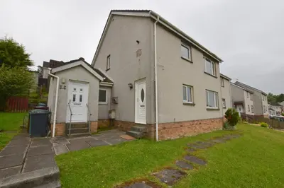 a house with a white door and a grass yard at Lovely 2 Bedroom Flat in a quiet location in Airdrie