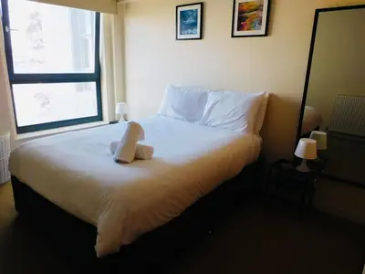 a teddy bear sitting on a bed in a bedroom at No 2 - Modern 2 Bed Apartment Close to Gla Airport & M8 in Paisley