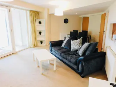 a living room with a black couch and a table at No 2 - Modern 2 Bed Apartment Close to Gla Airport & M8 in Paisley