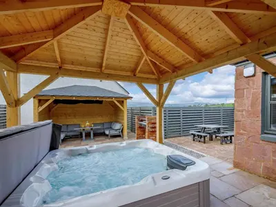 a hot tub on a patio with a wooden roof at Westertonhill Lodge - 3 Double Bedrooms Sleeps 8 With Private Hot Tub Hire Available in Balloch
