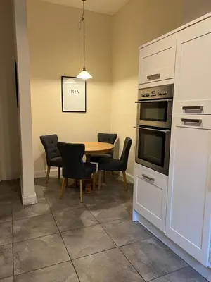 a kitchen with a table and a table and chairs at Victorian 3 BR main door flat, King size beds , large rooms in Glasgow