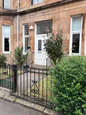 a black fence in front of a building with a white door at Victorian 3 BR main door flat, King size beds , large rooms in Glasgow