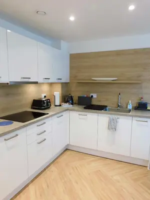 a kitchen with white cabinets and a wooden floor at Brand new gorgeous 2 bed Apt in Finnieston in Glasgow