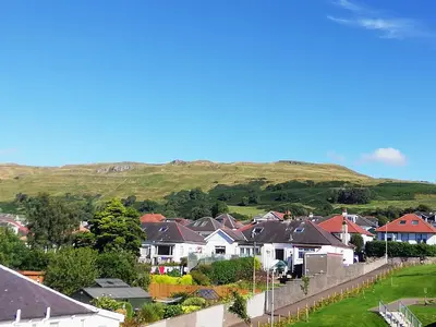 a village with houses and a hill in the background at Moorburn Heights in Largs