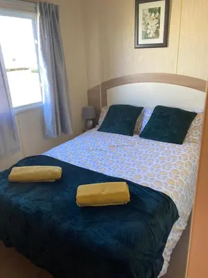 a bedroom with a bed with two yellow towels on it at 367 Caravan in Stevenston