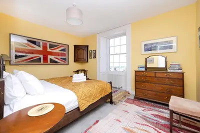 a bedroom with a bed and a table and a dresser at JOIVY Inviting Flat at the Heart of Edinburgh in Edinburgh