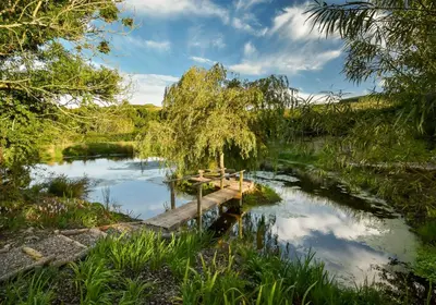 a small pond with a bridge in the middle at The Steading at Pitmeadow Farm in Dunning