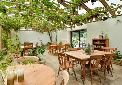 a patio with wooden tables and chairs and trees at The Steading at Pitmeadow Farm in Dunning