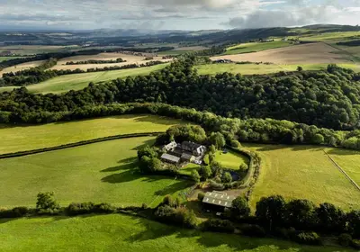 an aerial view of a house in a green field at The Steading at Pitmeadow Farm in Dunning