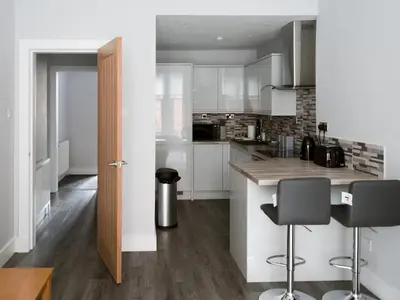 a kitchen with white cabinets and a counter with bar stools at Superb 1Bed Flat in Fabulous West End - Pass the Keys in Glasgow