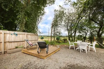 a patio with a table and chairs and a fence at Hayloft at Bonnyside House in Bonnybridge
