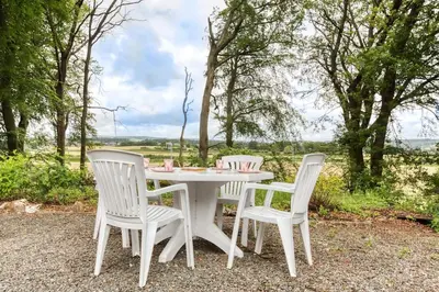 a white table with three white chairs and trees at Hayloft at Bonnyside House in Bonnybridge
