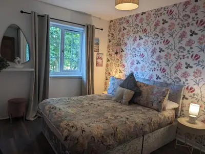 a bedroom with a bed with a floral wallpaper at Hayloft at Bonnyside House in Bonnybridge