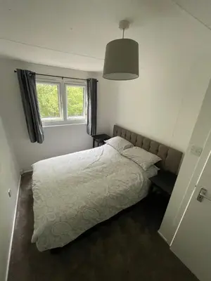 a bedroom with a white bed and a window at 1-Bedroom Chalet at Maryville Caravan Site - Uddingston, Glasgow in Uddingston