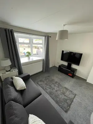 a living room with a couch and a flat screen tv at 1-Bedroom Chalet at Maryville Caravan Site - Uddingston, Glasgow in Uddingston