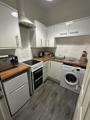 a kitchen with white cabinets and a washing machine at One bedroom flat in Oban town centre in Oban