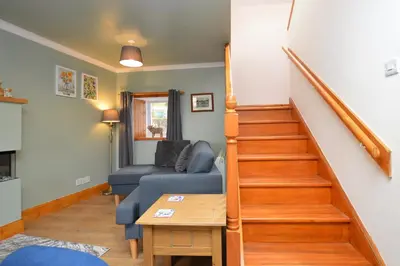 a living room with a blue couch and stairs at Chapelton Cottage in Strachur