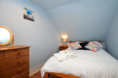 a bedroom with a bed with a dresser and a mirror at Chapelton Cottage in Strachur