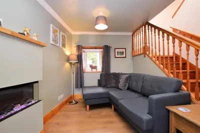 a living room with a couch and a staircase at Chapelton Cottage in Strachur