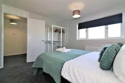 a bedroom with a large bed with a green blanket at Signature - Morland House in East Kilbride
