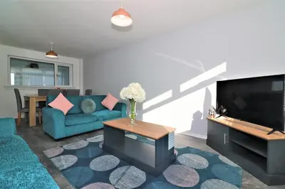 a living room with a blue couch and a tv at Signature - Morland House in East Kilbride