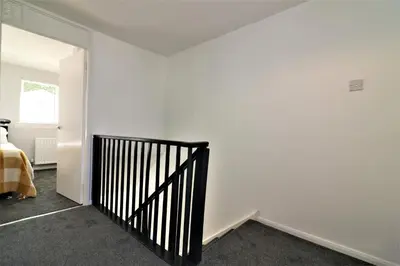 a white room with a black stair railing at Signature - Morland House in East Kilbride