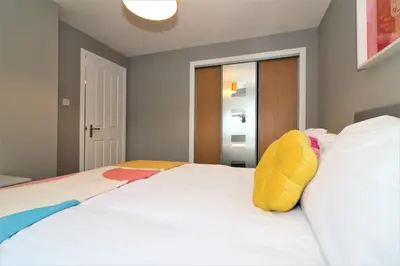 a bedroom with a large white bed with yellow pillows at Signature - Carnbroe House in Old Monkland