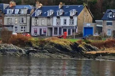 a group of houses next to a body of water at Superb Loch Side Apartment with Sea & Sunset Views in Helensburgh
