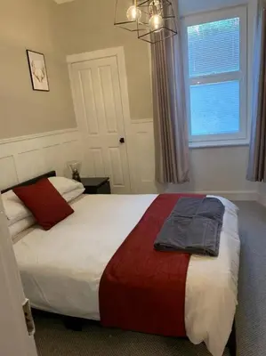 a bedroom with a large bed and a window at Superb Loch Side Apartment with Sea & Sunset Views in Helensburgh