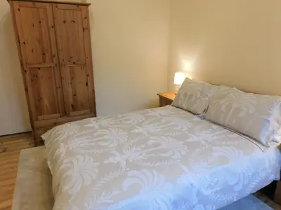 a bedroom with a bed and a wooden cabinet at Beautiful & spacious 2 bed apt in Glasgow West End in Glasgow