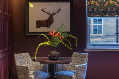 a table with a vase of flowers and two chairs at The Raeburn in Edinburgh