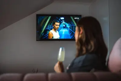 a woman sitting on a couch holding a video game controller at The West End Loft - 5* Retreat - Private Parking! in Glasgow