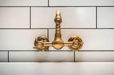 a gold bathroom fixture on a white tiled wall at The West End Loft - 5* Retreat - Private Parking! in Glasgow