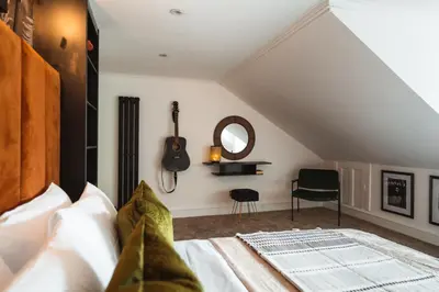 a bedroom with a bed and a guitar on the wall at The West End Loft - 5* Retreat - Private Parking! in Glasgow