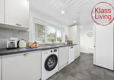 a kitchen with a washing machine in a white kitchen at West End House by Klass Living Bellshill in Bellshill