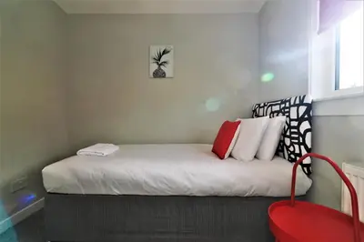 a small bed with white sheets and red pillows at Signature - Sydney House in East Kilbride