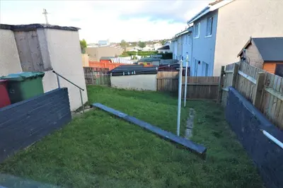 a backyard with a fence and a yard withgrass at Signature - Sydney House in East Kilbride