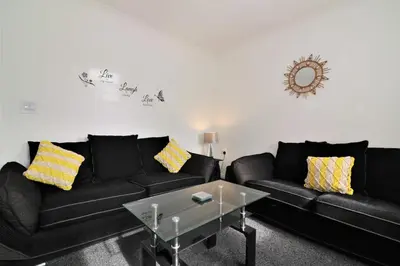 a living room with two black couches and a table at Signature - Kirkhill Middle in Kirkmuirhill